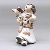 A grandmother holding a math book open and singing with the three children in her lap, click or tap to see a larger version