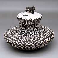 Click for a larger view A lidded black on white low shouldered jar with a recurved neck and decorated with a spiraling whirling logs and geometric design
by Barbara and Joseph Cerno Sr of Acoma