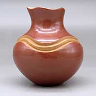 A red jar with a pie crust rim and decorated with a carved geometric design painted with micaceous clay, click or tap to see a larger version