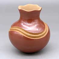 A red jar with a pie crust rim and decorated with a carved geometric design painted with micaceous clay
 by Dominique Toya of Jemez