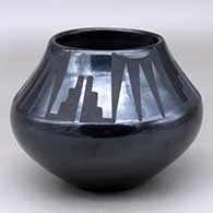 A black on black jar decorated with a four panel bat wing, kiva step and geometric design above the shoulder
 by Maria Martinez of San Ildefonso