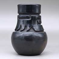 A tall neck black jar decorated with a carved stylized avanyu design around the neck, click or tap to see a larger version
