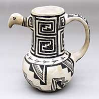 A black-on-white mug with a handle, a bird head and decorated with lock-and-keys, kiva steps, bird prints, and geometric design
 by Michael Kanteena of Laguna