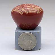 A miniature red seed pot decorated with a sgraffito rabbit and geometric design, click or tap to see a larger version