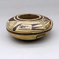 A black-on-yellow seed pot with a four-panel geometric design above the shoulder and a Fred Harvey Hopi Villages tag
 by Unknown of Hopi