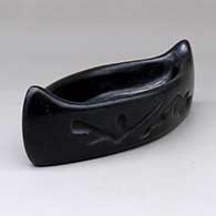 A black canoe polished inside and carved outside with a geometric design
 by Unknown of Santa Clara