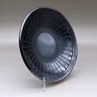 A black on gunmetal black plate decorated with a ring of feathers and geometric design, click or tap to see a larger version