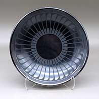 A black on gunmetal black plate decorated with a ring of feathers and geometric design
 by Maria Martinez of San Ildefonso