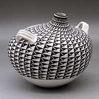 A large black on white canteen with handles and decorated with a crane and fish medallion surrounded by a spiral mesa geometric design, click or tap to see a larger version