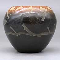 A black bowl with a sienna rim and decorated with a sgraffito avanyu and geometric design, click or tap to see a larger version