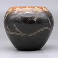 A black bowl with a sienna rim and decorated with a sgraffito avanyu and geometric design, click or tap to see a larger version