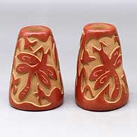 A pair of red candlestick holders carved with a dragonfly, plant and geometric design
 by Sharon Naranjo Garcia of Santa Clara