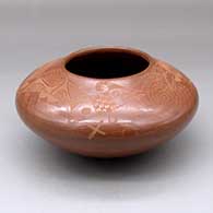 A red jar decorated above the shoulder with a sgraffito avanyu and geometric design
 by Ron Martinez of Isleta
