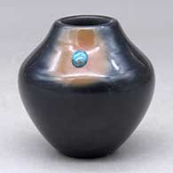 A small black jar with a sienna spot and an inlaid stone
 by Dora Tse Pe of San Ildefonso