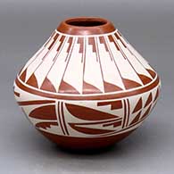 A white-on-red jar decorated with a band-of-feathers and geometric design around the body and neck
 by Geraldine Sandia of Jemez