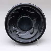 A black plate carved with an avanyu design
 by Toni Roller of Santa Clara