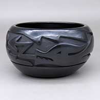 A black bowl carved around the body with an avanyu design
 by Mida Tafoya of Santa Clara