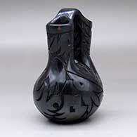 A black wedding vase carved with an avanyu, sun face and geometric design, click or tap to see a larger version