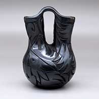 A black wedding vase carved with an avanyu, sun face and geometric design, click or tap to see a larger version
