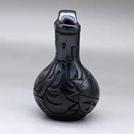 A black wedding vase carved with an avanyu, sun face and geometric design, click or tap to see a larger version