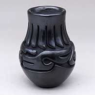 A black jar carved with a stylized avanyu and ring-of-feathers design
 by Teresita Naranjo of Santa Clara