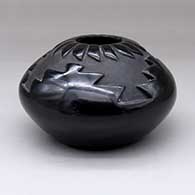 A black seed pot decorated with a carved four-panel kiva step and ring-of feathers design above the shoulder
 by Judy Tafoya of Santa Clara