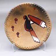 A shallow golden micaceous bowl with a notched rim and decorated with fire clouds and painting of a bird, flowers and a cross inside
 by Jeralyn Lujan Lucero of Taos