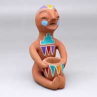 A polychrome Tesuque Rain God with a pot in his lap and decorated with a geometric design
 by Unknown of Tesuque