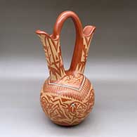 A large red wedding vase decorated with a sgraffito double avanyu, feather,bear paw and geometric design with inlaid stones and strands of heishi beads
 by Sammy Naranjo of Santa Clara