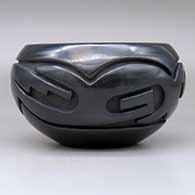 An open black bowl carved around the body with an avanyu and geometric design, click or tap to see a larger version