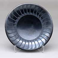 A black-on-gunmetal-black plate decorated with a ring of feathers design
 by Maria Martinez of San Ildefonso