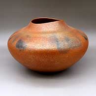A large orange micaceous jar with an organic opening and fire clouds
 by Lonnie Vigil of Nambe