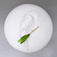 A white seed pot decorated with a carved parrot applique and a feather
 by Wilfred Garcia of Acoma