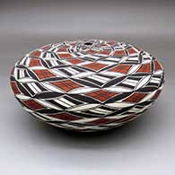 A polychrome seed pot decorated with a pumpkin seed snowflake and spiral geometric design
 by Cletus Victorino of Acoma