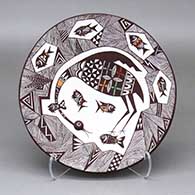 A polychrome plate decorated with a cloudeater, fish, fine line and geometric design with some appliques
 by Carolyn Concho of Acoma