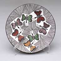 A small polychrome plate decorated with several butterfly wing appliques and a butterfly, fine line and geometric design, from the in-shop demonstration
 by Alisha Sanchez of Acoma