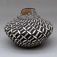 A black-on-white jar with an organic opening and a pumpkin seed snowflake and geometric design
 by Sandra Victorino of Acoma
