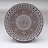 A polychrome plate with a North Star fine line, pumpkin seed snowflake and geometric design
 by Rebecca Lucario of Acoma