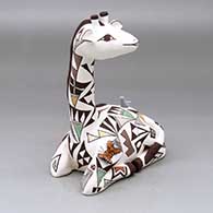 A polychrome sitting giraffe figure with bird, lizard, and butterfly appliques with a geometric design all over
 by Judy Lewis of Acoma