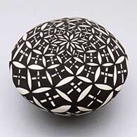 A black-on-white seed pot decorated with a pumpkin seed snowflake geometric design
 by Cletus Victorino of Acoma