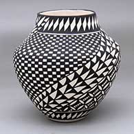 A black-on-white jar decorated with a checkerboard, pumpkin seed snowflake and spiraling geometric design
 by Sandra Victorino of Acoma