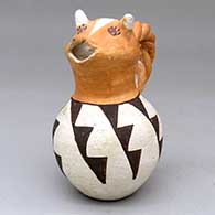 A polychrome cream pitcher with a cow head spout, twisted handle and a black-on-white geometric design around the body
 by Mabel Brown of Acoma