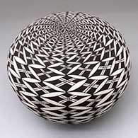 A black-on-white seed pot decorated with a pumpkin seed snowflake and geometric design
 by Cletus Victorino of Acoma