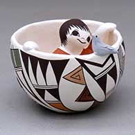 A polychrome bowl with a bird perched on the side and a child kneeling inside, decorated around the body with a geometric design
 by Judy Lewis of Acoma