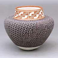 A polychrome jar decorated with a sgraffito geometric design around the neck and with a painted checkerboard-based graphic design below
 by Frederica Antonio of Acoma