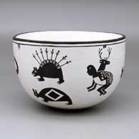 A black-on-white bowl decorated on the outside with a series of classic Mimbres animals and human dancers
 by Carmel Lewis of Acoma