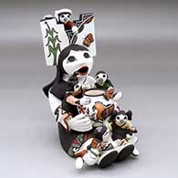 A sitting grandmother storyteller figure with a tablito on her head and with five children, butterflies, a turtle, a bird and a pot o n her
 by Marilyn Ray of Acoma