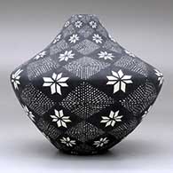 A black on white jar decorated with a flower, fineline and geometric design, click or tap to see a larger version