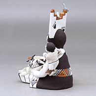 A sitting grandmother storyteller figure wearing a tablito, holding two children and a pot, birds, cat, butterfly and lady bug, click or tap to see a larger version