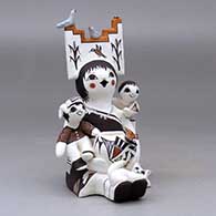 A sitting grandmother storyteller figure wearing a tablito, holding two children and a pot, birds, cat, butterfly and lady bug, click or tap to see a larger version